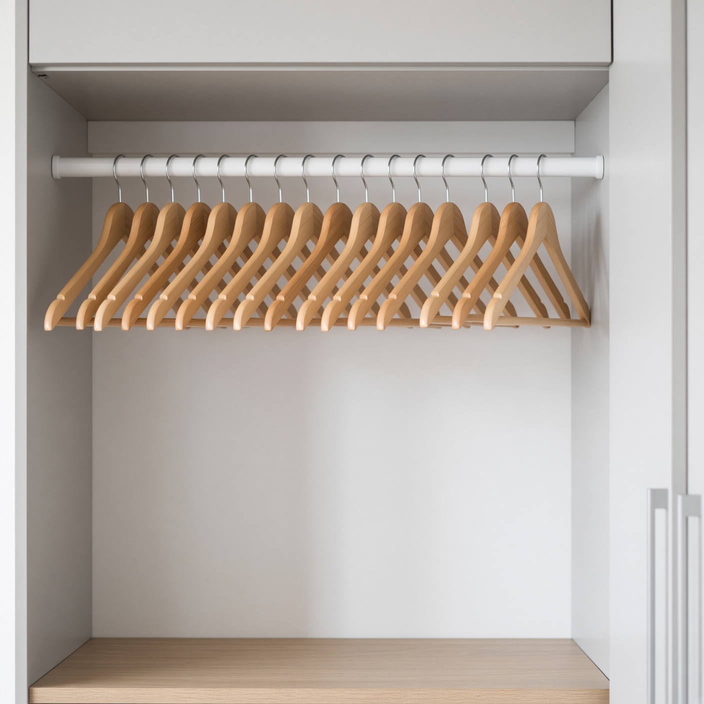 Twenty wooden hangers on a wardrobe rail.