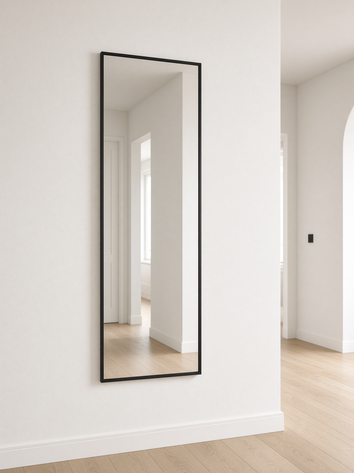 A black iron wall mirror, 50 by 100 centimetres, in a pale hall.